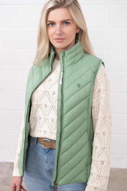 Lighthouse womens padded gilet green worn by woman over cream sweater and blue jeans