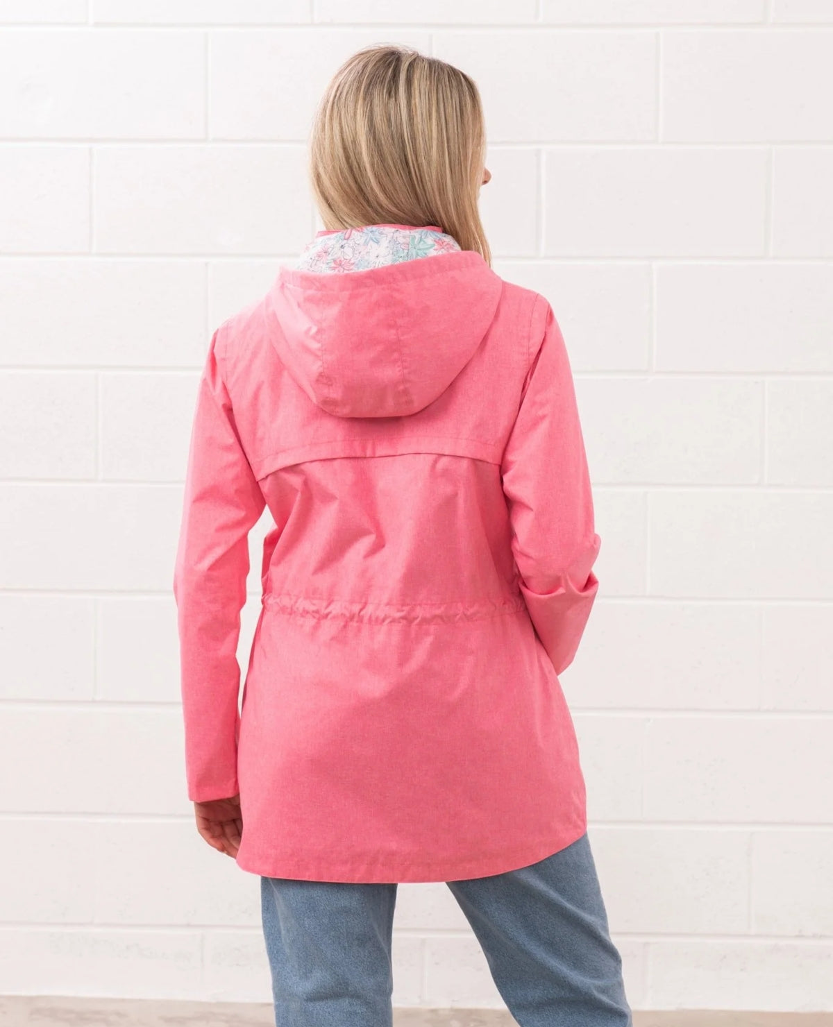 Back view of Lighthouse womens pink waterproof jacket with hood and adjustable waist worn by model