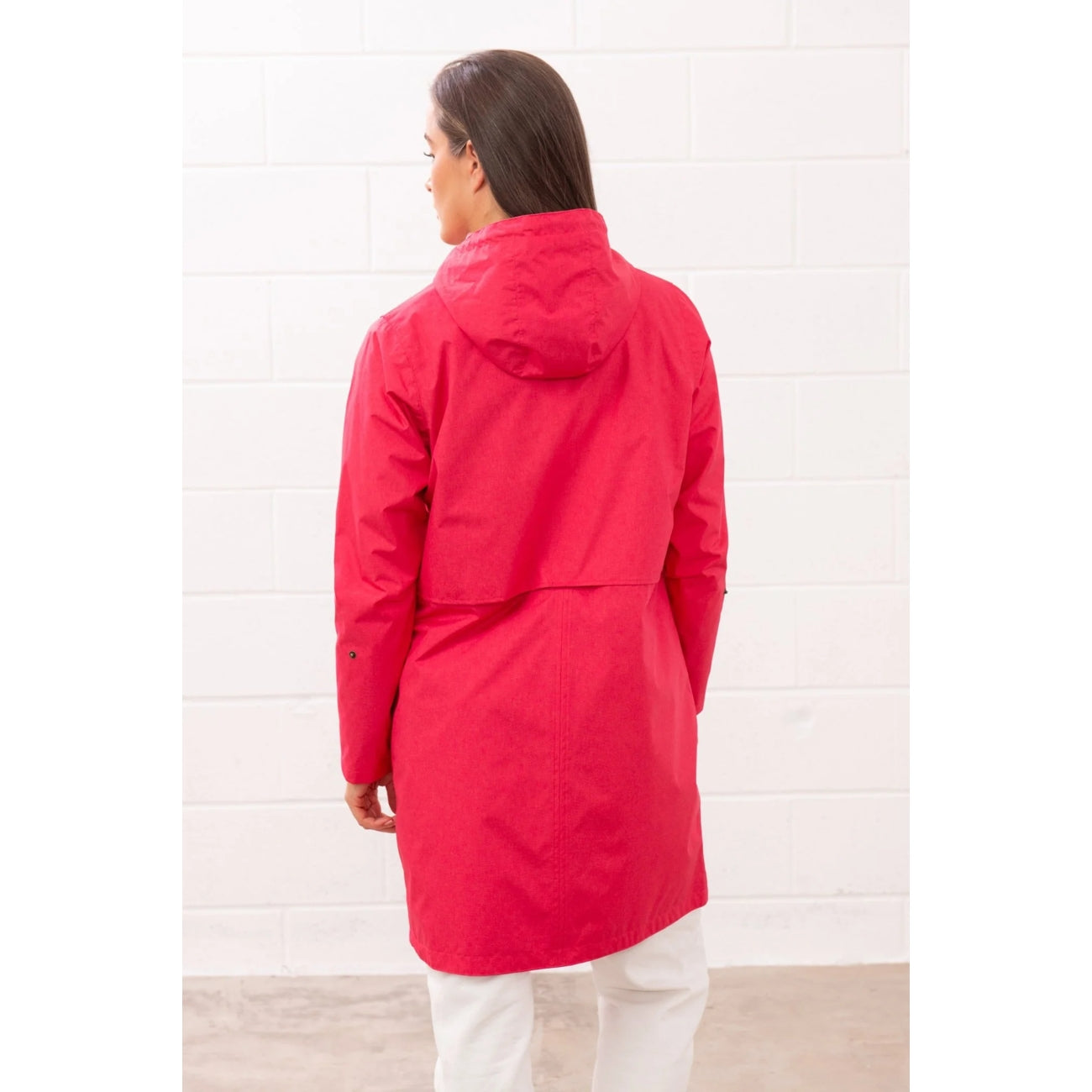 Back view of a woman wearing a Lighthouse Pippa 3/4 length waterproof raincoat in Raspberry pink/red.