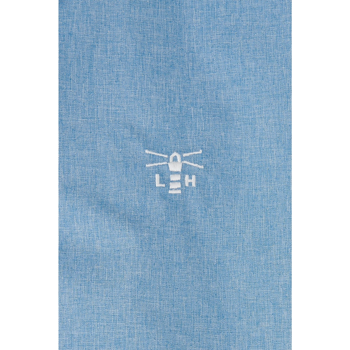 Close-up view of the logo on a Lighthouse Pippa coat in white on a Soft Denim Blue waterproof fabric.