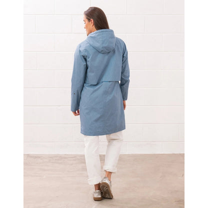 Back view of a woman wearing a Lighthouse Pippa 3/4 length waterproof raincoat in Soft Denim Blue.