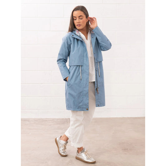 Front view of a woman wearing a Lighthouse Pippa 3/4 length waterproof raincoat in Soft Denim Blue.