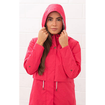 Woman wearing a Lighthouse Pippa 3/4 length waterproof raincoat in Raspberry pink/red with the hood up.