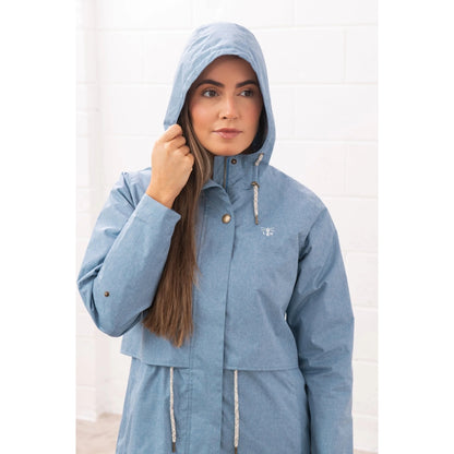 Woman wearing a Lighthouse Pippa 3/4 length waterproof raincoat in Soft Denim Blue with the hood up.
