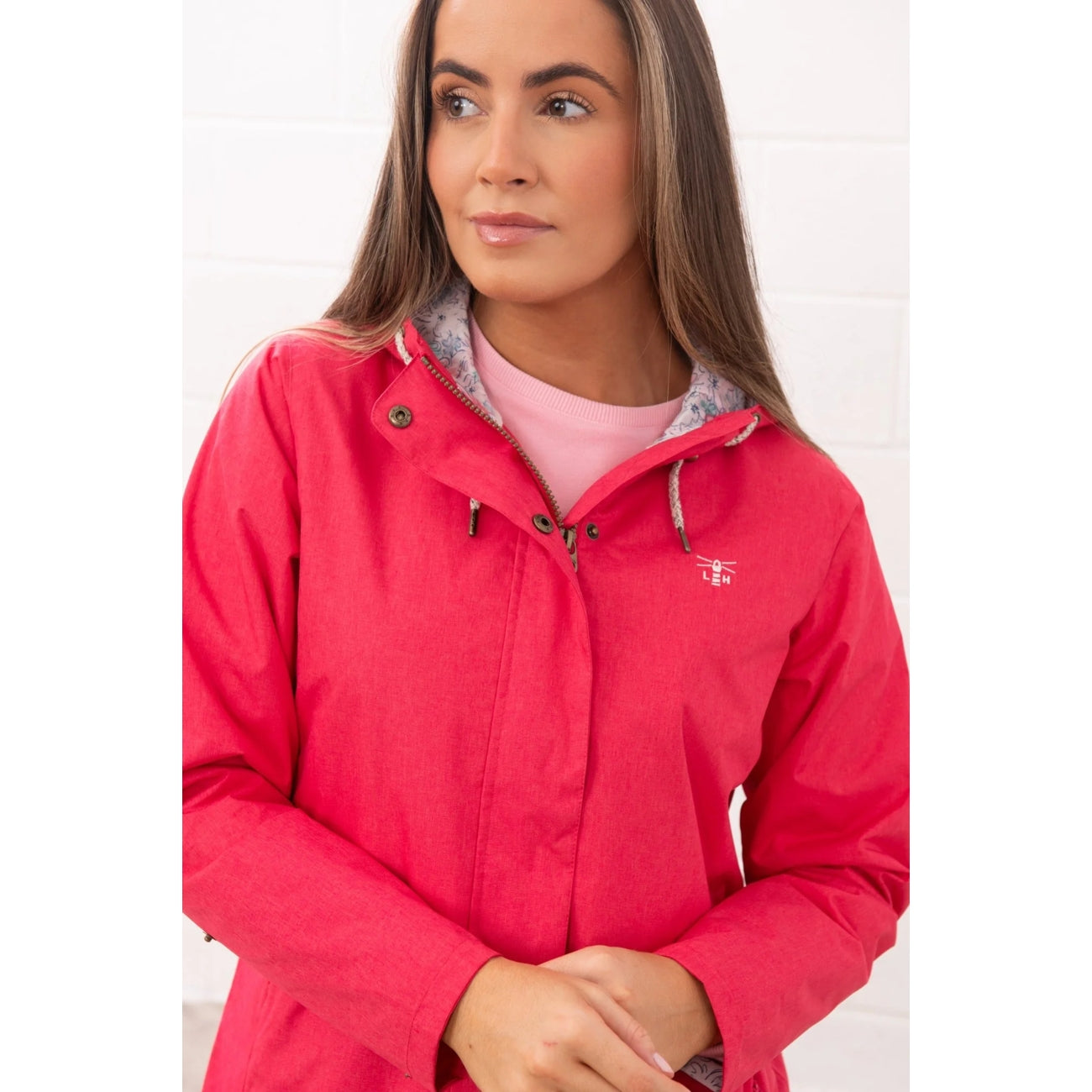 Front view of a woman wearing a Lighthouse waterproof Pippa 3/4 length raincoat in Raspberry pink/red.
