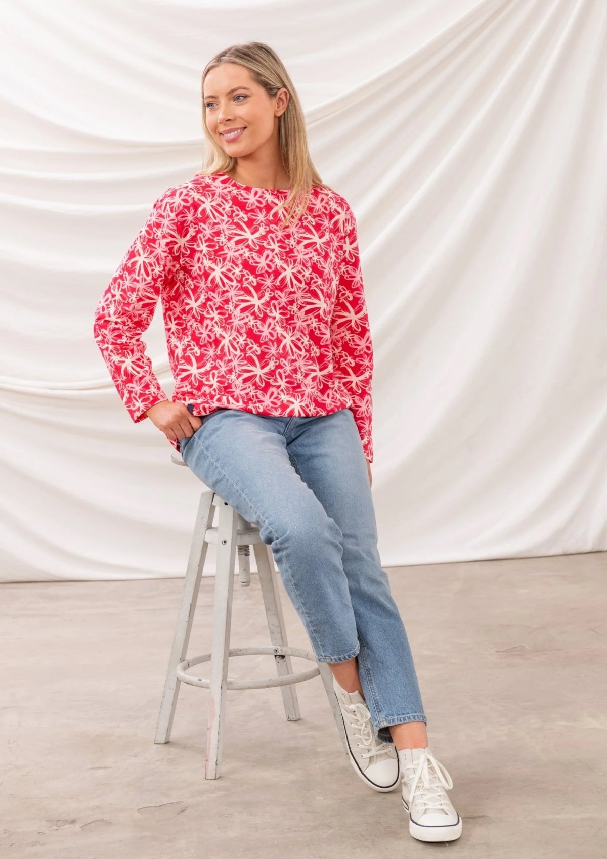 Lighthouse womens Raspberry Floral Tee worn by model sitting on stool with light wash jeans and white sneakers