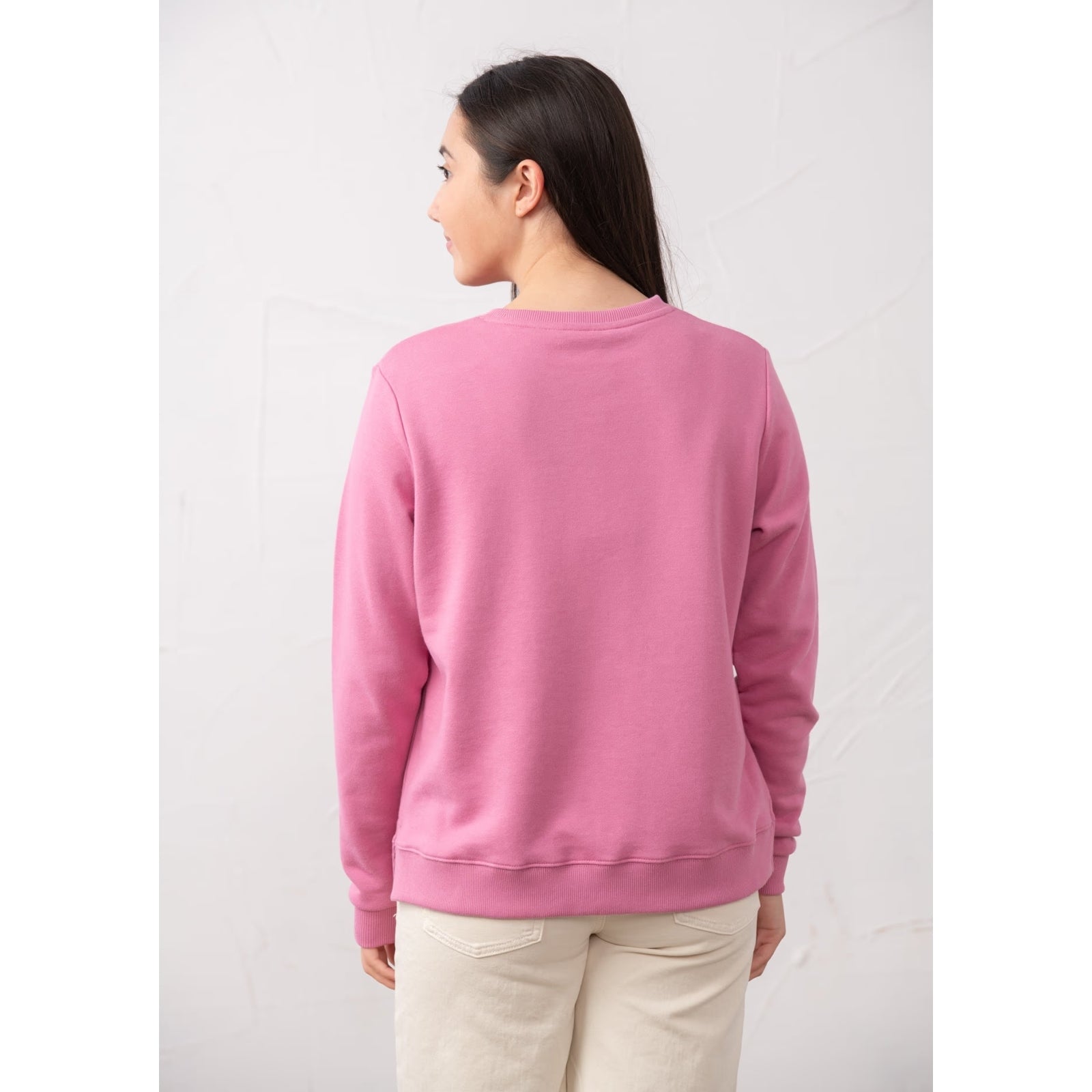 Back view of a woman wearing a Lighthouse Seaside crew neck sweatshirt in Pink.
