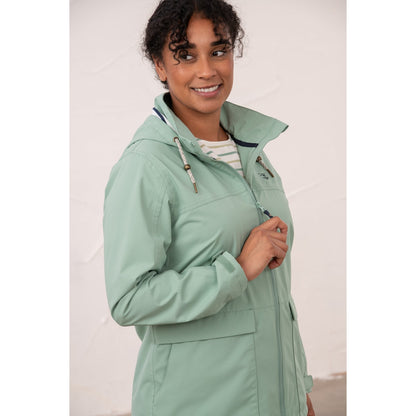 Close-up view of a woman wearing a Lighthouse waterproof Beachcomber II waterproof jacket in Basil green.