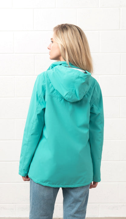 Lighthouse womens waterproof jacket teal with hood shown from the back on a model in casual jeans