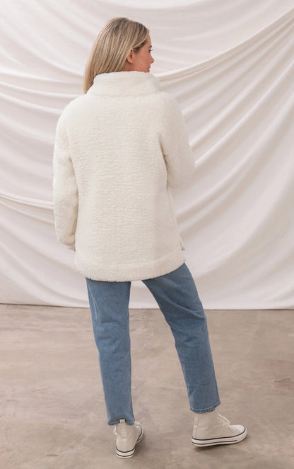 Back view of woman wearing white Lighthouse womens zip fleece with high collar and blue jeans