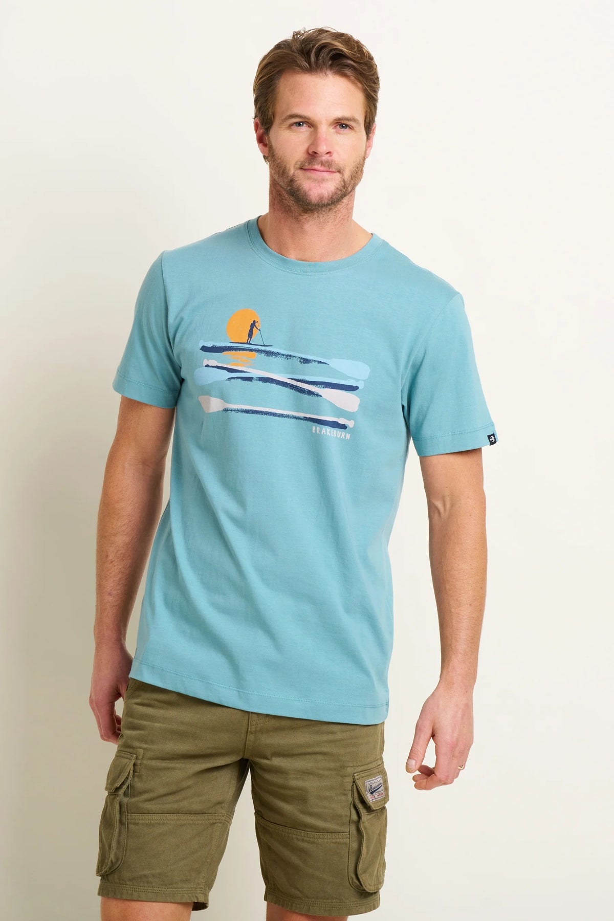 Front view of a mens Brakeburn paddleboard tee blue with graphic sunset and paddleboard design on front