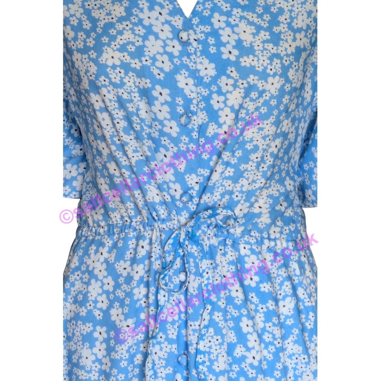 Close up of a tie waistline on a Mudd & Water womens Alyssa wrap dress in blue with a white floral pattern on a white background