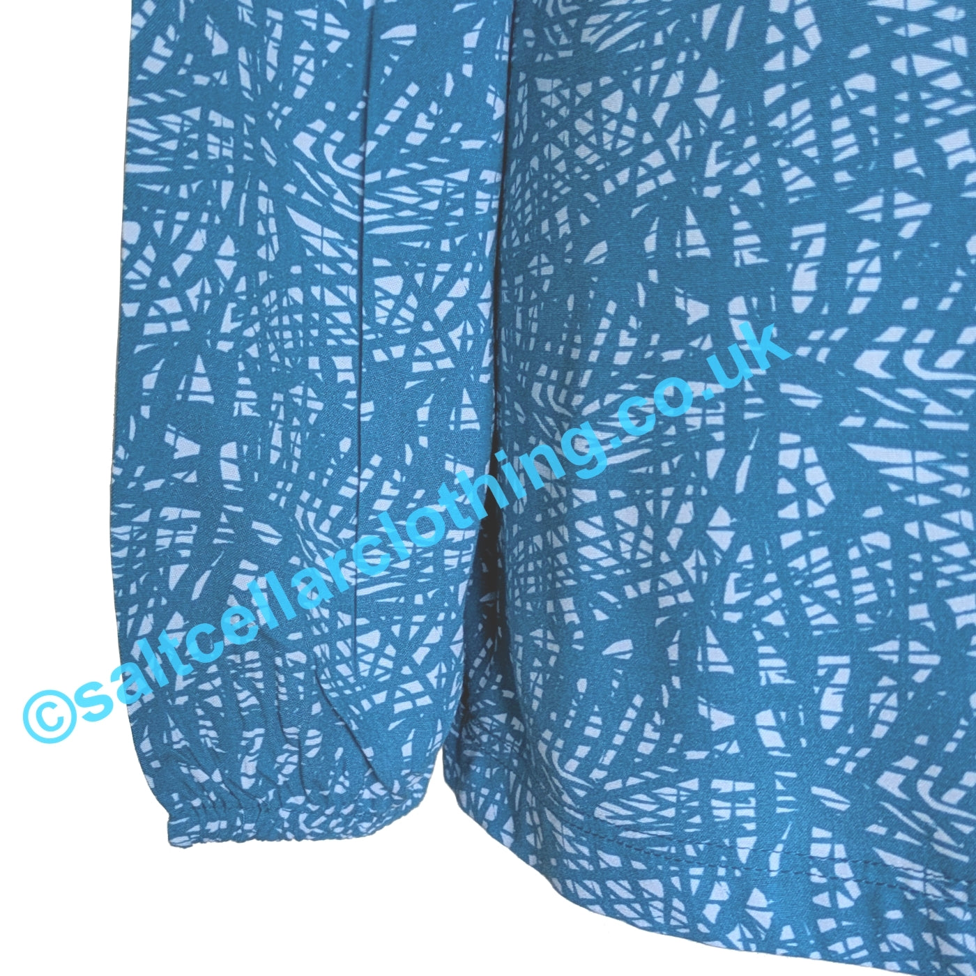 Close up of the elasticated cuff of a womens Mudd & Water Bailey blouse in teal blue with a white abstract pattern