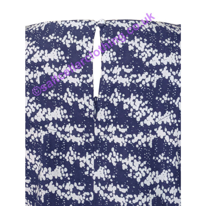 Close up of the teardrop back button fastening of a Mudd & Water womens Call Top in navy with a white dotty print on a white background