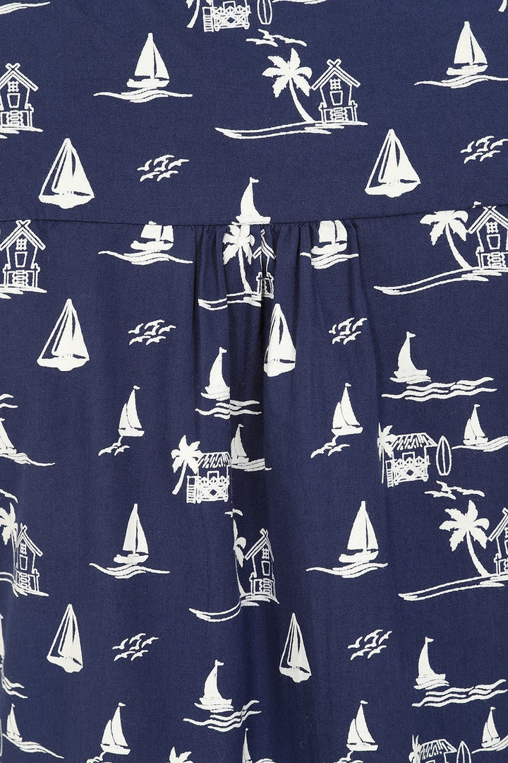 Closeup of a Mudd & Water womens Sunrise Blouse fabric with pleats in navy with a tropical nautical sailboat and palm tree pattern