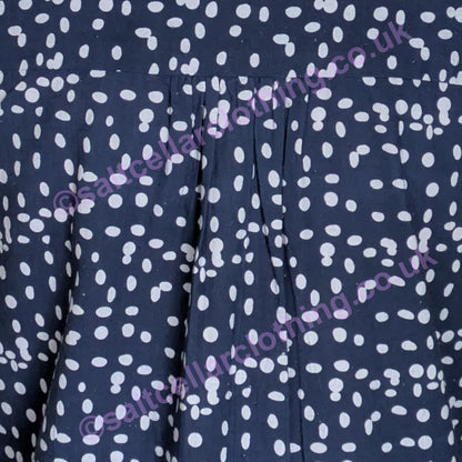 Close-up of navy fabric with a white dot pattern and pleats on a womens Mudd & Water Sunrise Blouse