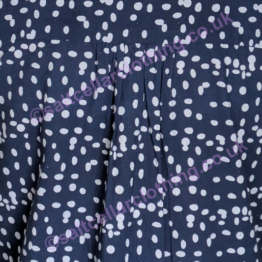 Close-up of navy fabric with a white dot pattern and pleats on a womens Mudd & Water Sunrise Blouse