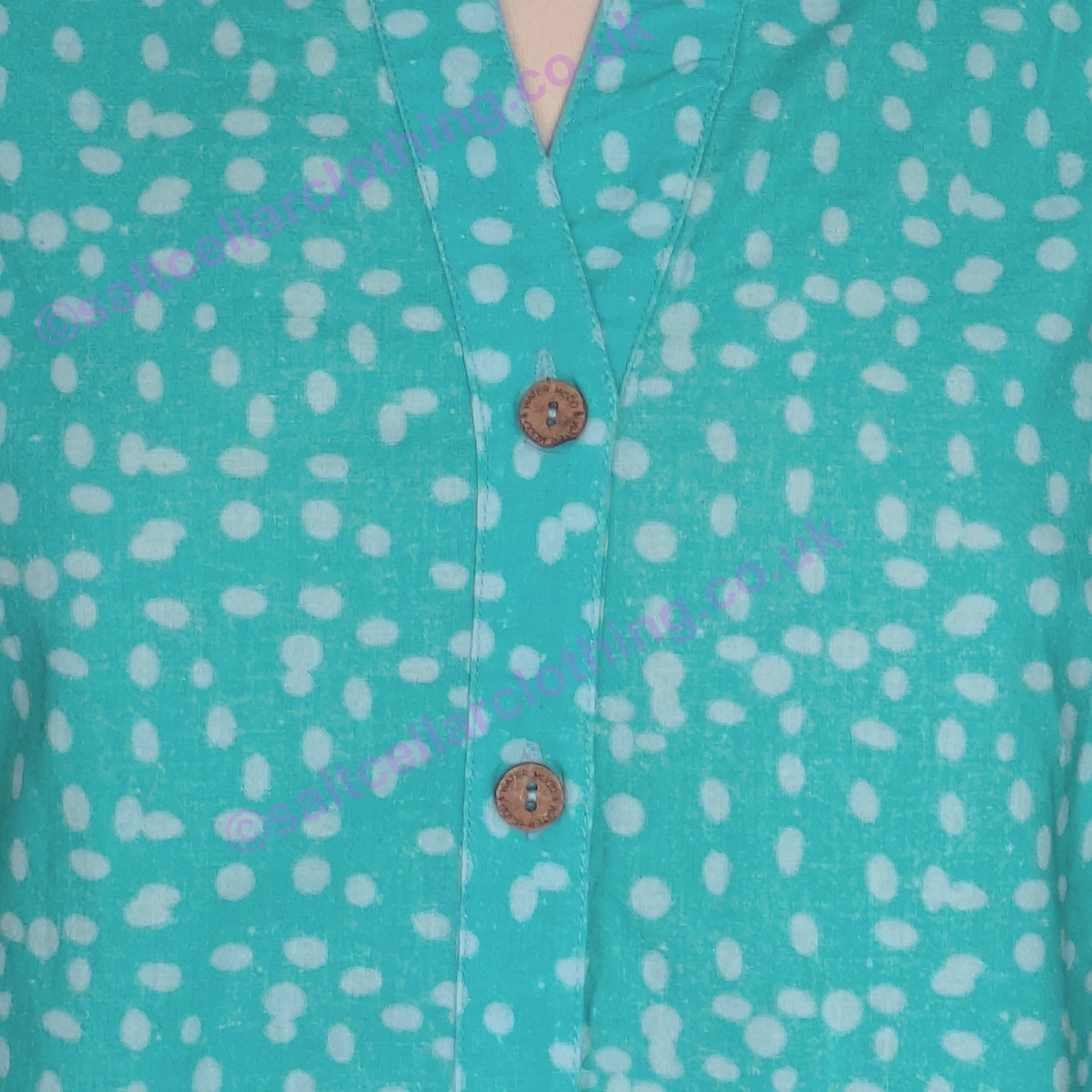 Close-up of a Mudd & Water turquoise Sunrise blouse with a polka dot pattern and wooden buttons.