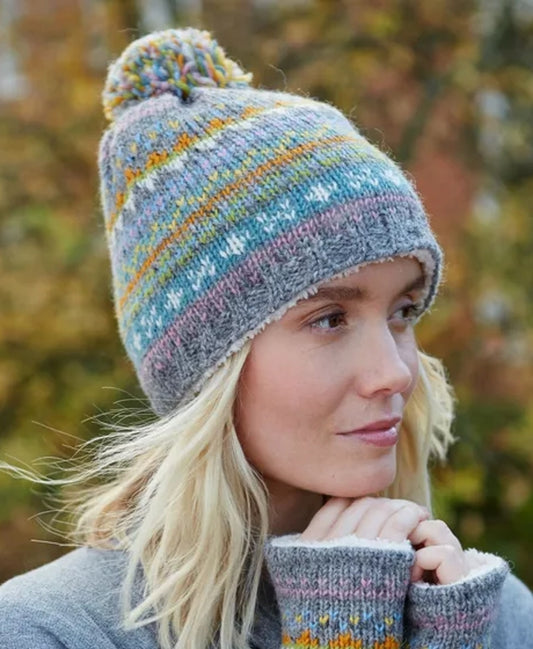 Woman wearing a grey and multicolour Fair Isle pattern Pachamama knitted bobble hat