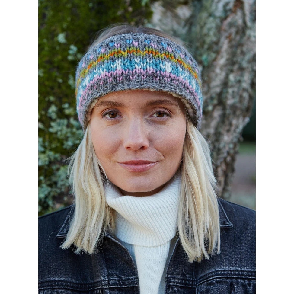 Woman wearing a colourful knitted Pachamama Braemar headband outdoors