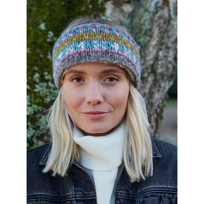 Woman wearing a colourful knitted Pachamama Braemar headband outdoors
