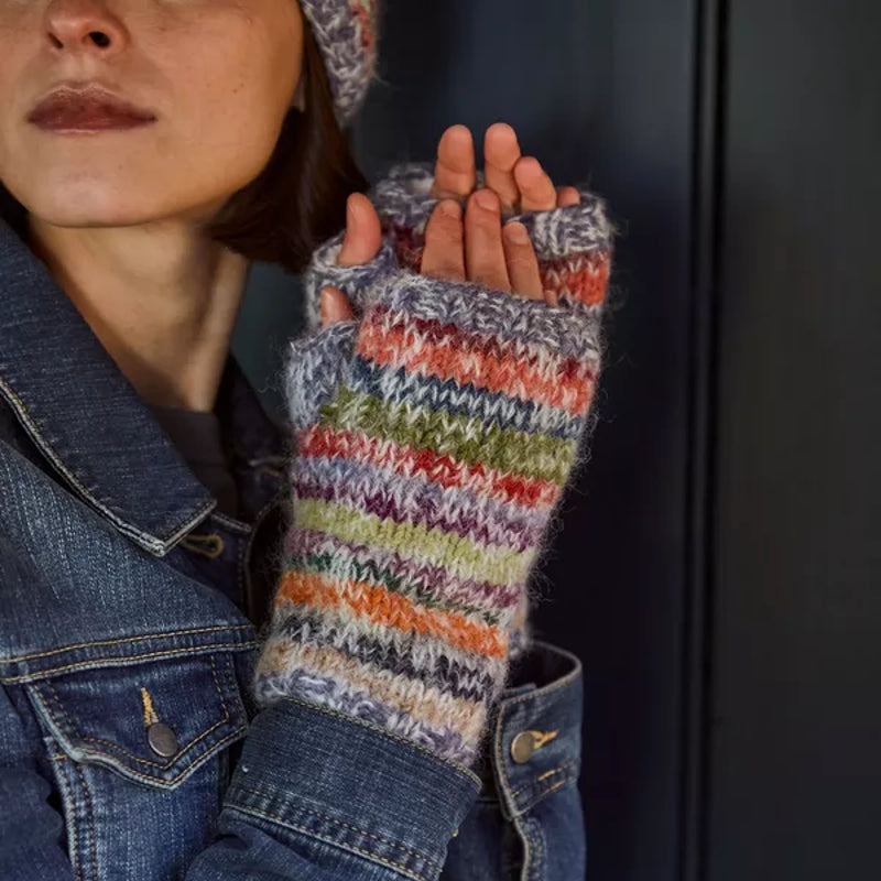 Woman wearing colourful striped Pachamama handwamers with a denim jacket.