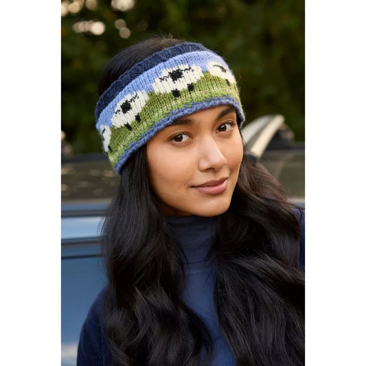 Woman wearing a Pachamama sheep pattern knitted headband with a blurred outdoor background