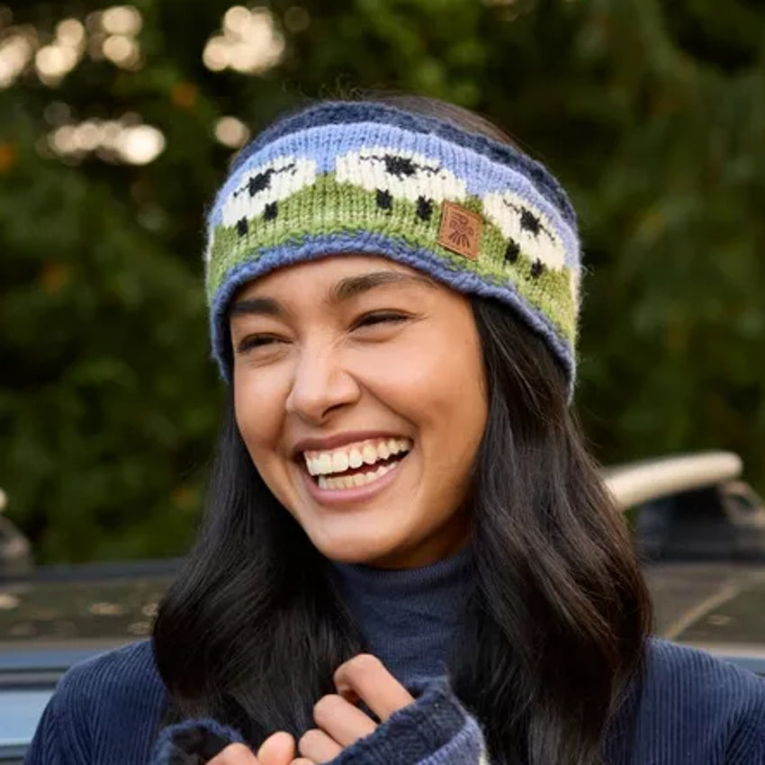 Woman wearing a sheep pattern Pachamama knitted beanie with a blurred outdoor background