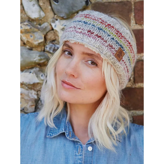 Woman wearing a colourful Pachamama knitted headband against a stone wall background