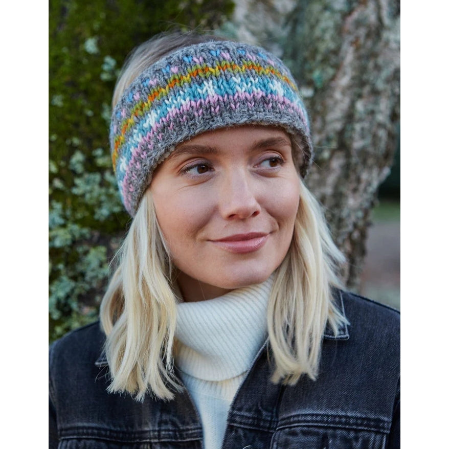 Woman wearing a colourful knitted Pachamama Braemar headband outdoors