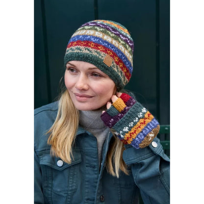 Person wearing colourful knitted Pachamama fingerless gloves in a multicolour Fair Isle pattern outdoors.