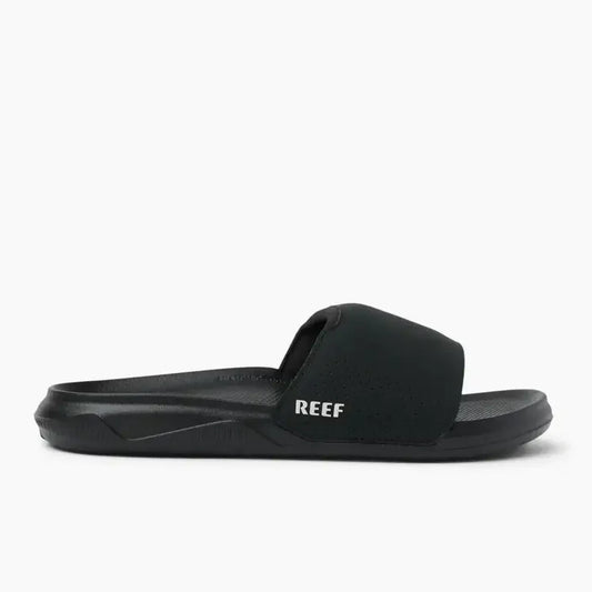 Side view of a mens Reef Tailslide slider sandal in black with a padded strap and printed strap logo.