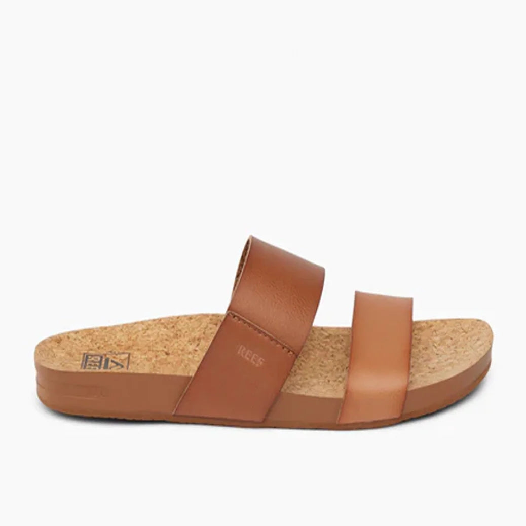 Side view of a womens Reef Cushion Vista faux leather double strap sandal in Espresso Duo brown, with cork footbed and debossed logo on the straps.