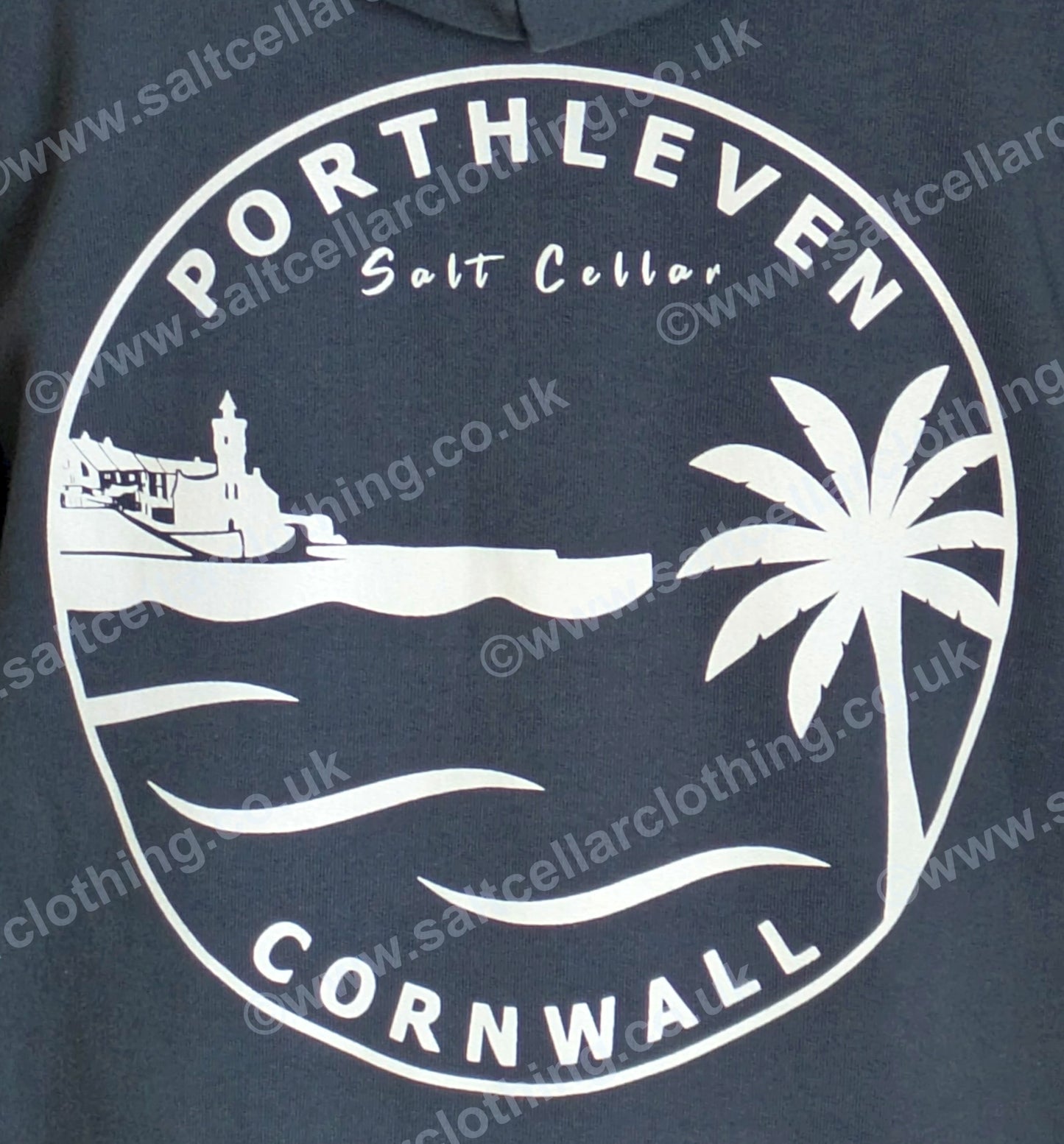 Close-up view of the print on a Petrol Blue full zip hoodie, featuring a white circular graphic, with a clocktower and harbour, palm tree, waves, and the text 'PORTHLEVEN Salt Cellar' and 'CORNWALL'.