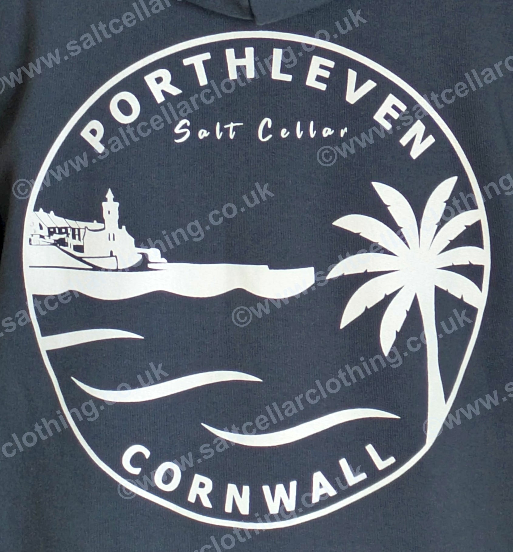 Close-up view of the print on a Petrol Blue full zip hoodie, featuring a white circular graphic, with a clocktower and harbour, palm tree, waves, and the text 'PORTHLEVEN Salt Cellar' and 'CORNWALL'.