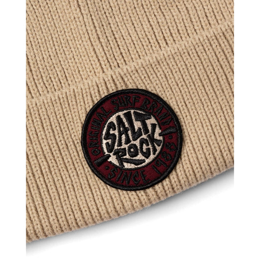 Beige knitted beanie with a Salt Rock logo patch on a white background