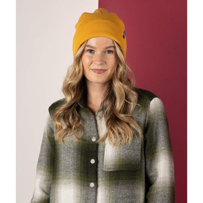 Woman wearing a Saltrock yellow Ok beanie and plaid shirt against a two-tone background