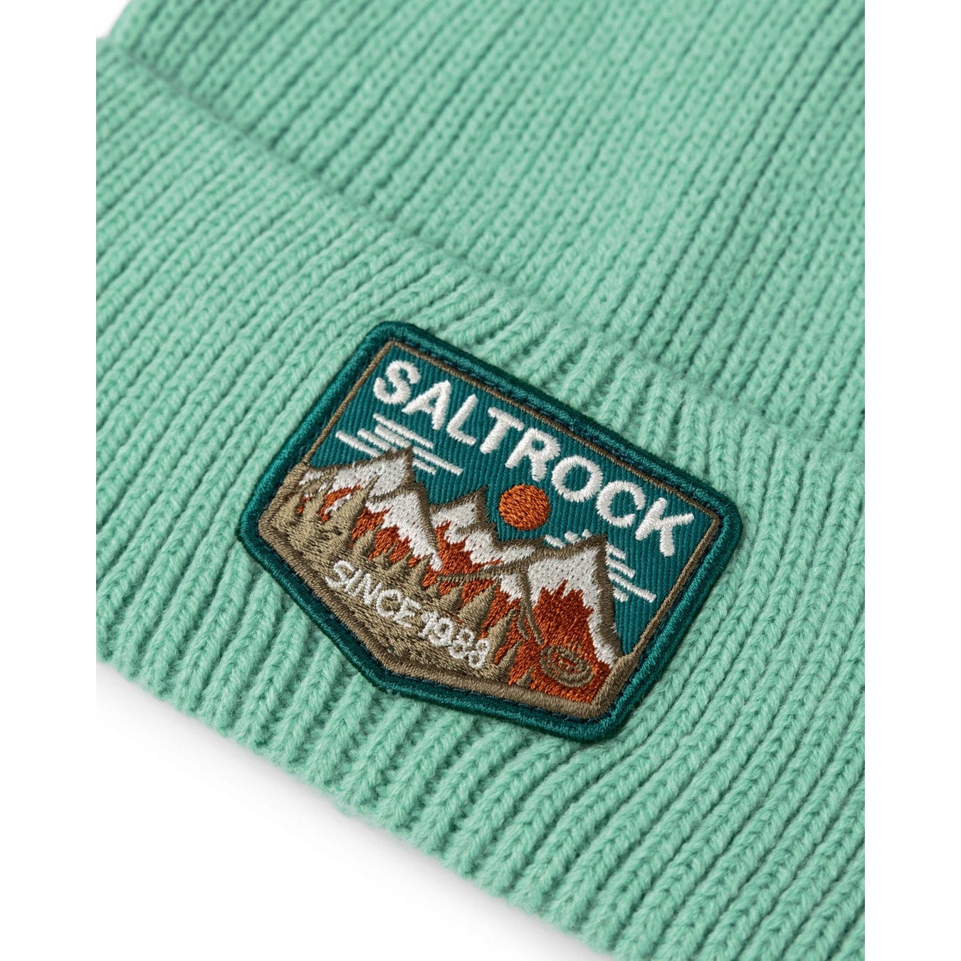 Close up of a Saltrock Uplands light green beanie with a Saltrock patch featuring mountain design