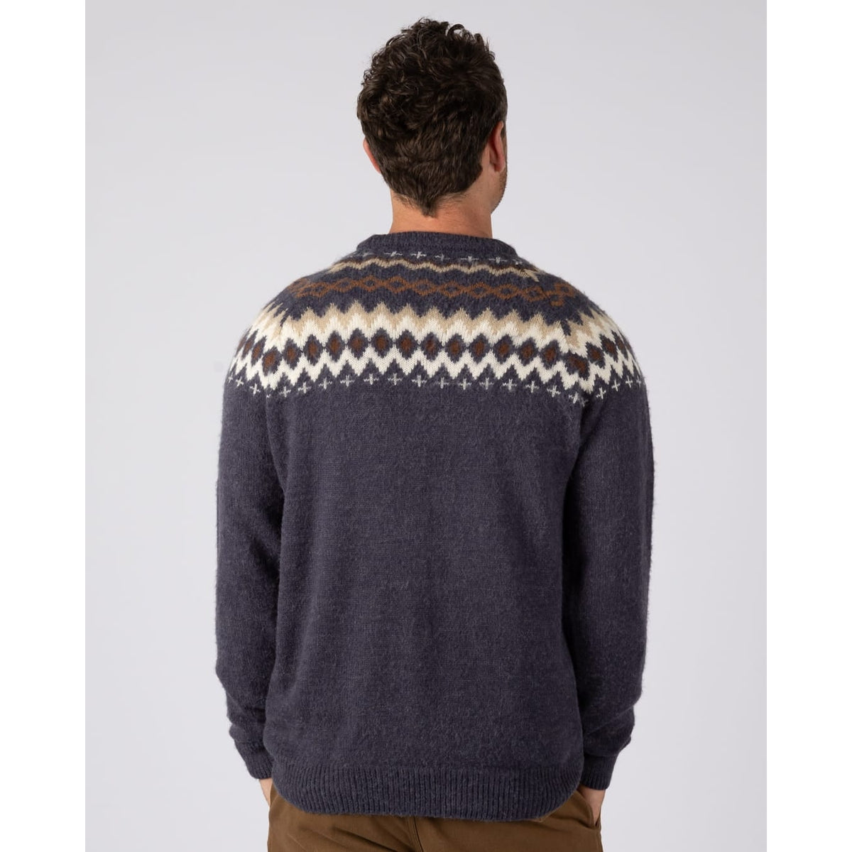 Back view of a man wearing a  Saltrock Fairisle Rock crew neck knitted jumper in blue with a geometric Fairisle style pattern across the chest and shoulders.