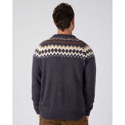 Back view of a man wearing a  Saltrock Fairisle Rock crew neck knitted jumper in blue with a geometric Fairisle style pattern across the chest and shoulders.