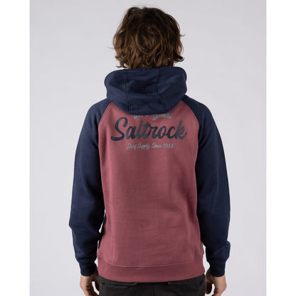 Back view of a man wearing a Saltrock Postcard Script hoodie in dark pink with navy blue sleeves and hood and large logo print
