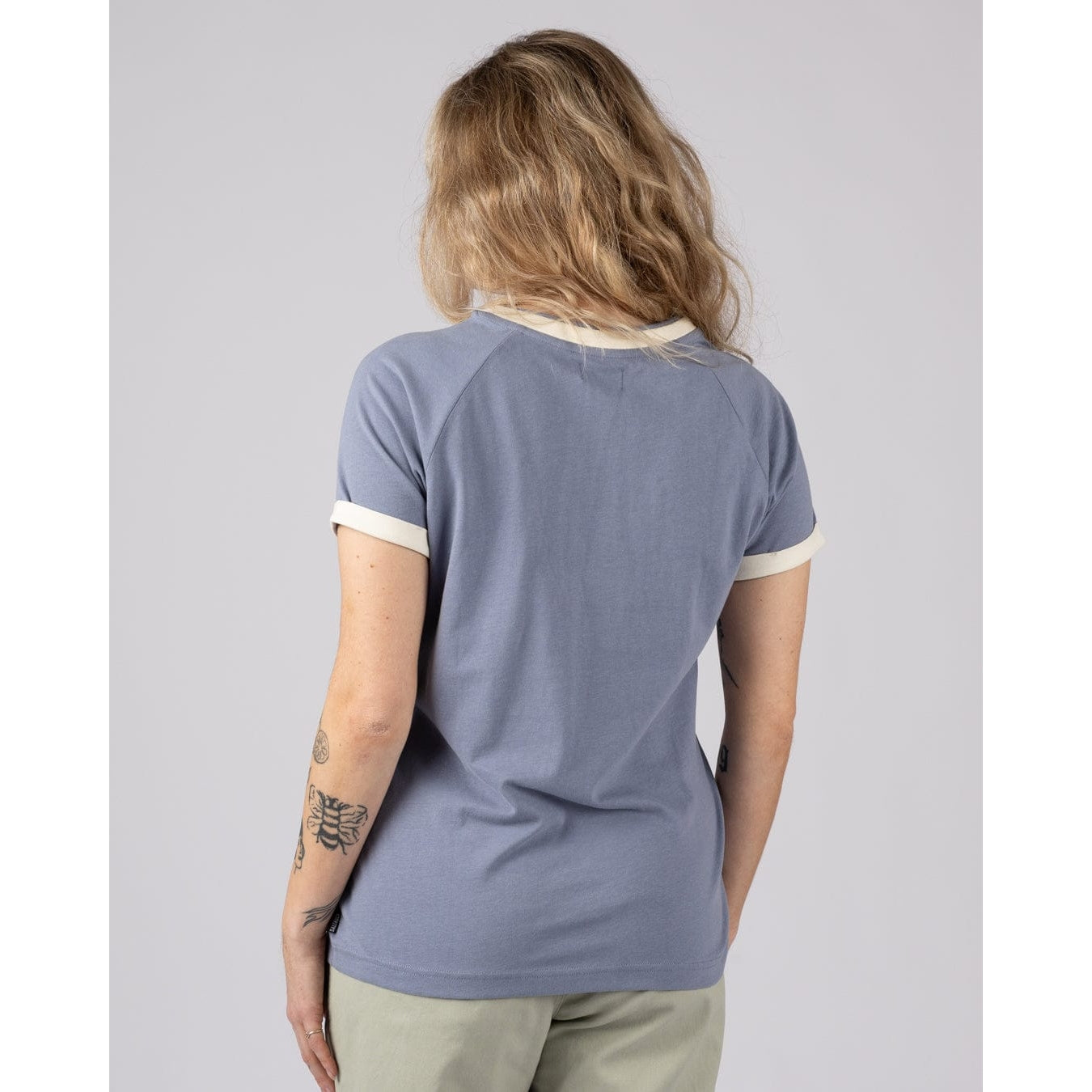 Back view of a woman wearing a blue Saltrock Links short sleeve t-shirt with cream trim on a grey background