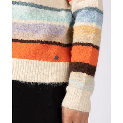 Close-up view of a cuff and metal logo fob of a woman wearing a Saltrock Lyris crew neck knitted jumper in an orange, cream and multicolour striped pattern.