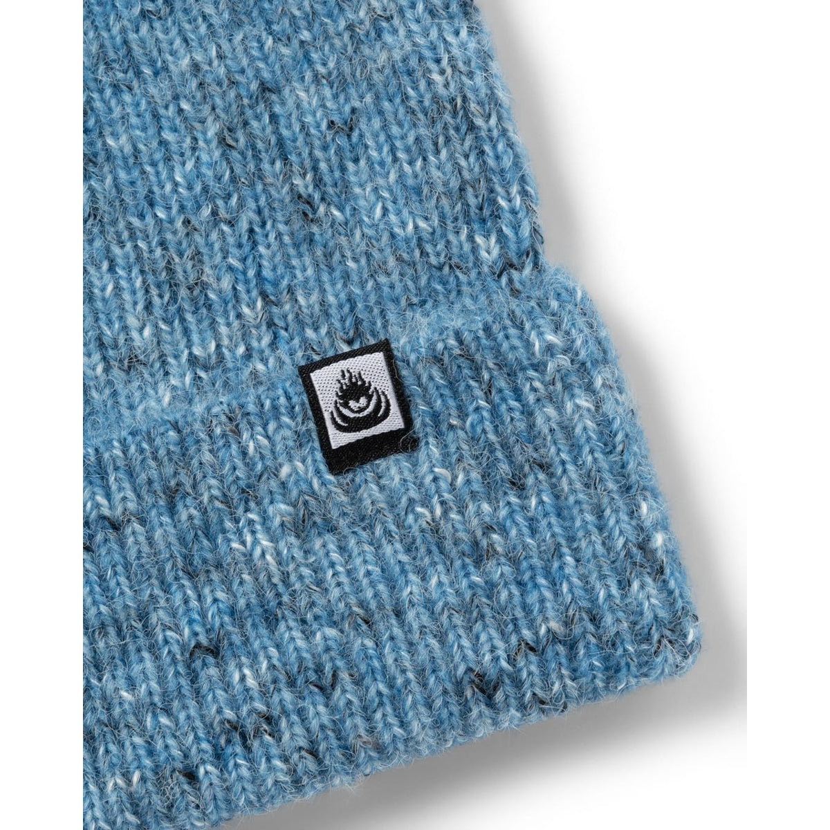 Close-up view of the turn back hem, logo label and flecked bright blue yarn of an adults Saltrock knitted Brushed Maine beanie.