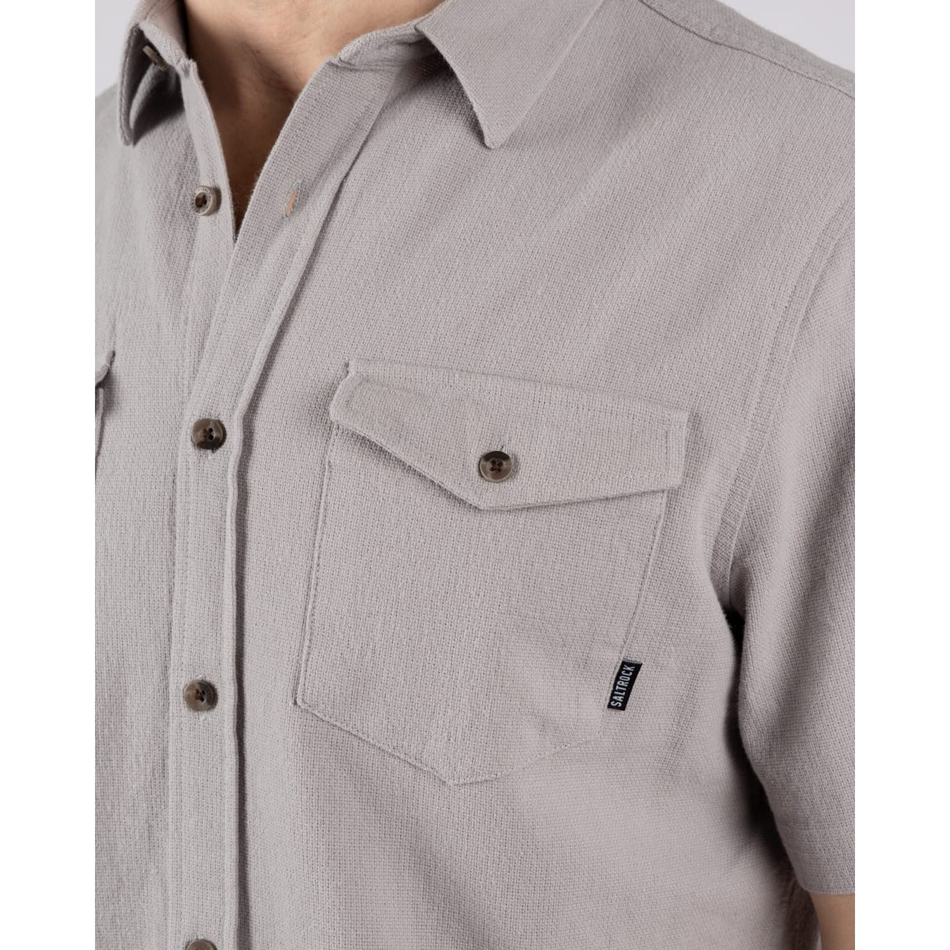 Close-up view of a chest button pocket on a men's Saltrock short sleeve Polperro button shirt in grey with a waffle texture.