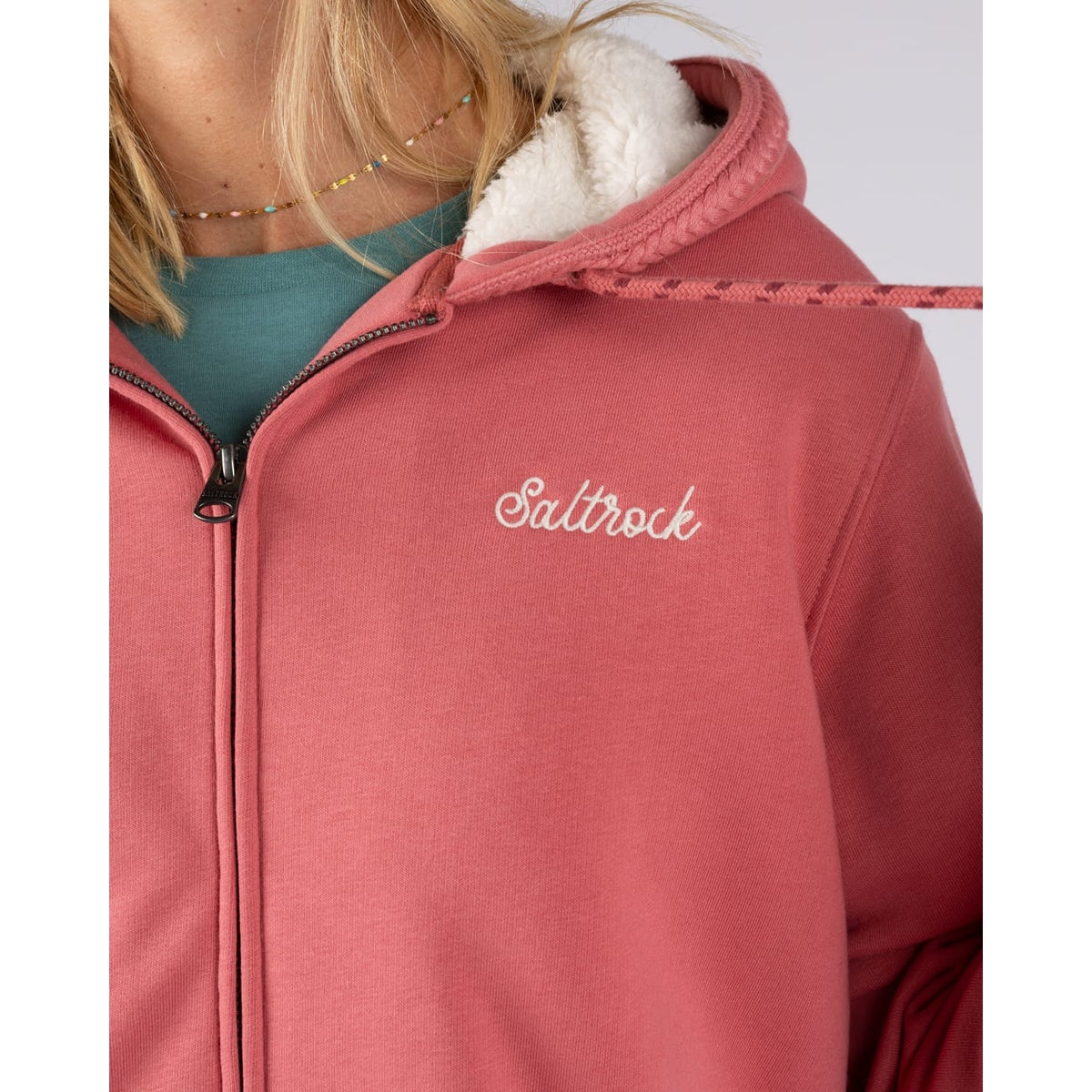 Close-up view of the small chest logo of a Saltrock womens full zip Borg lined Tamsin hoodie in Pink