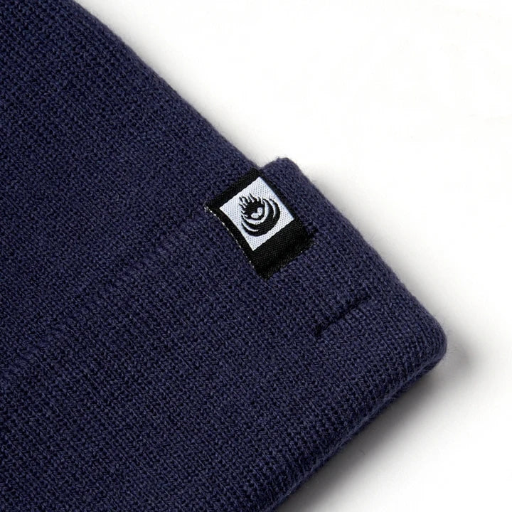 Close-up view of an adults Saltrock Ok knitted beanie in blue with a turn back hem and small logo label.