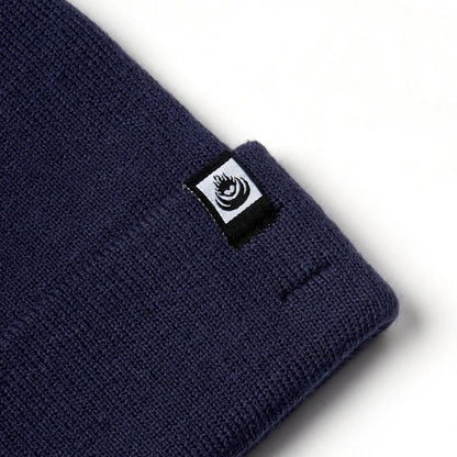 Close-up view of an adults Saltrock Ok knitted beanie in blue with a turn back hem and small logo label.