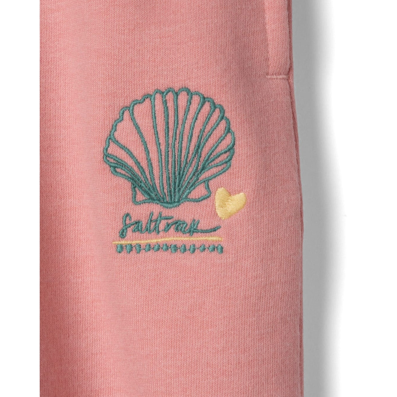 Close-up view of an embroidered shell logo on a pair of Saltrock kids Norie jogger trousers in pink