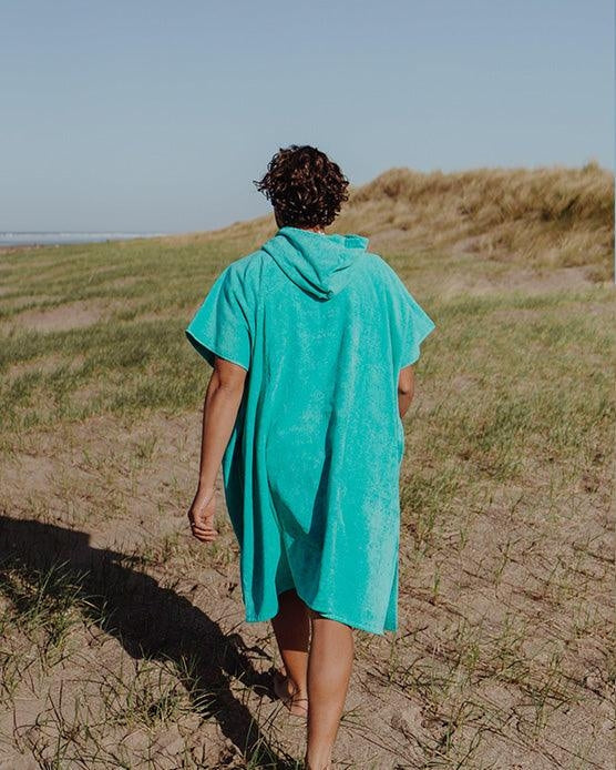 Person wearing Saltrock Corp changing towel robe in Turquoise walking on grassy sand dunes